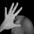Woman with bare shoulders raising her hand to cover her face.