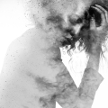 Woman with eyes closed and hand on head double exposed with a monochromatic paint splatter effect.