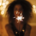 Woman holding a sparkler in front of her.
