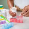 Close up of hands putting pills in a pill box.