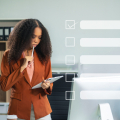 Woman looking at tablet in an office with a checklist superimposed on top of the image.