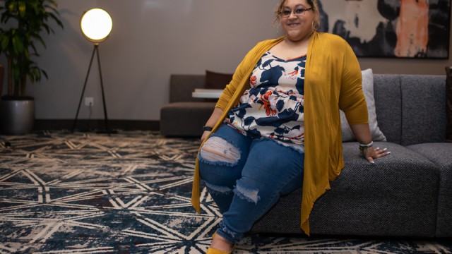 Marissa Gonzalez, sitting on a sofa, smiling.