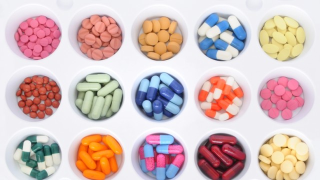 Several bowls of different colored medications in rows.
