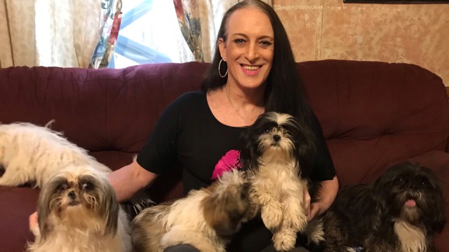 Katie Willingham, smiling, sitting on sofa with five small dogs.