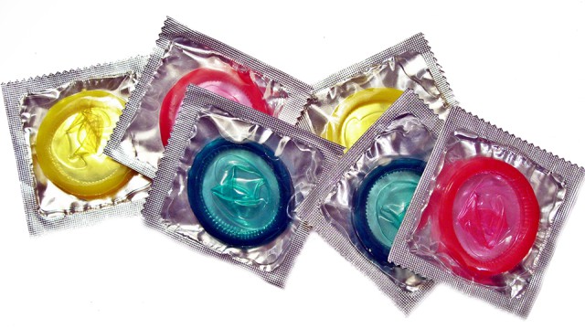 Varios condones de colores visibles a través de envases transparentes.