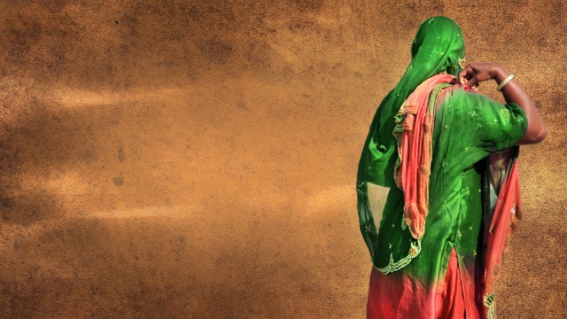 Espalda de mujer en sari frente a una pared.