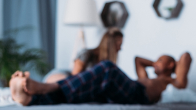 Blurry photo of two people lying on bed talking.