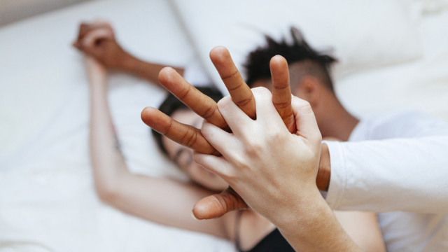 Dos personas en la cama tomadas de la mano.