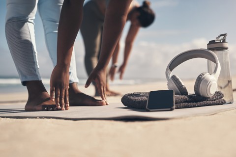 Two women stretching at the beach.