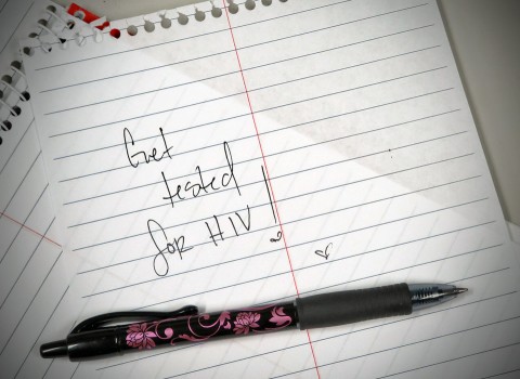 Page torn out of notebook with handwritten note that reads "Get tested for HIV!".