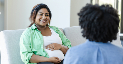 Pregnant person smiling and talking to healthcare provider.