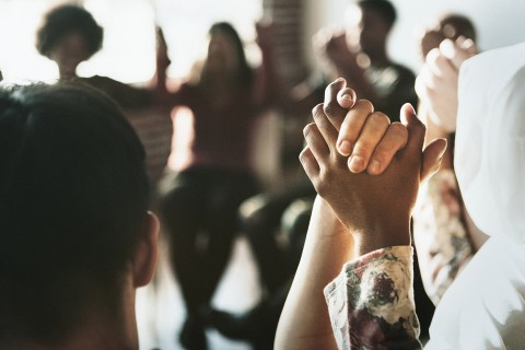 Blurry picture of a small circle of women holding raised hands.