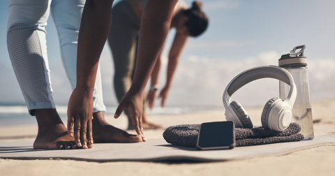 Two women stretching at the beach.