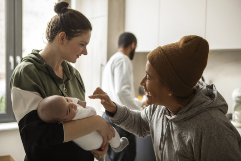 Tres personas en una cocina, una de ellas sosteniendo a un bebé.