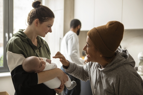 Three people in a kitchen, one holding a baby.