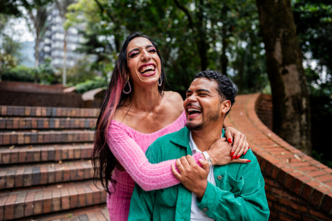 Two people walking together and laughing while embracing. 