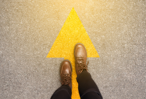 Close up of feet in shoes on walking forward on yellow arrow.