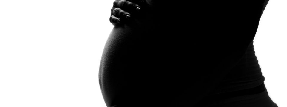 Silueta del vientre de una mujer embarazada, sus manos acunándolo.
