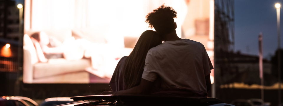 Silhouette of the backs of two people watching an outdoor movie.
