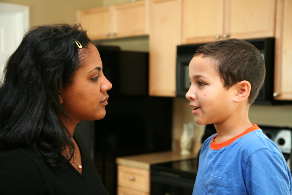 Child and woman talking in a kitchen.
