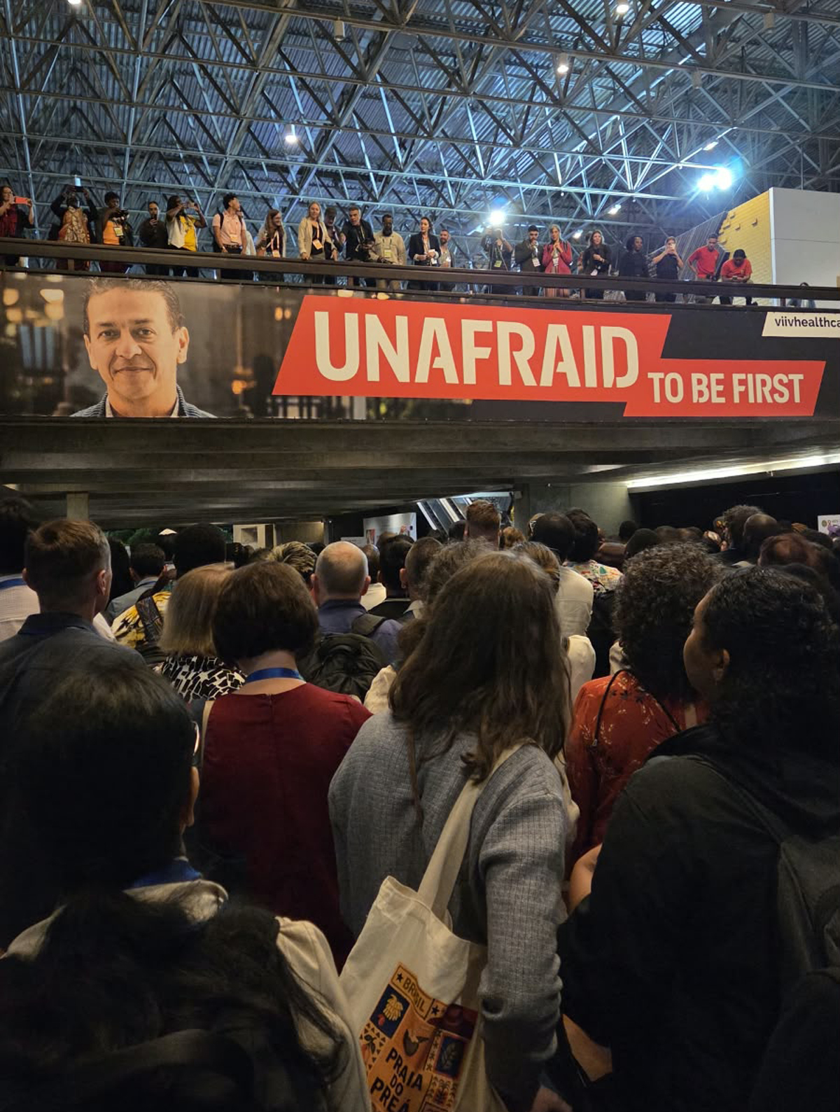 Sign at AIDS 2026 reading "Unafraid to be first" in big crowd of attendees.