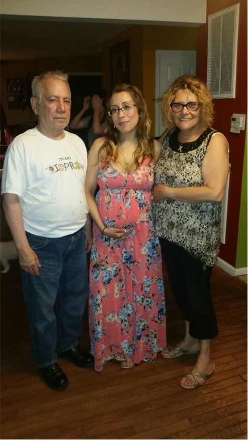 Escalice, pregnant, standing with family members.